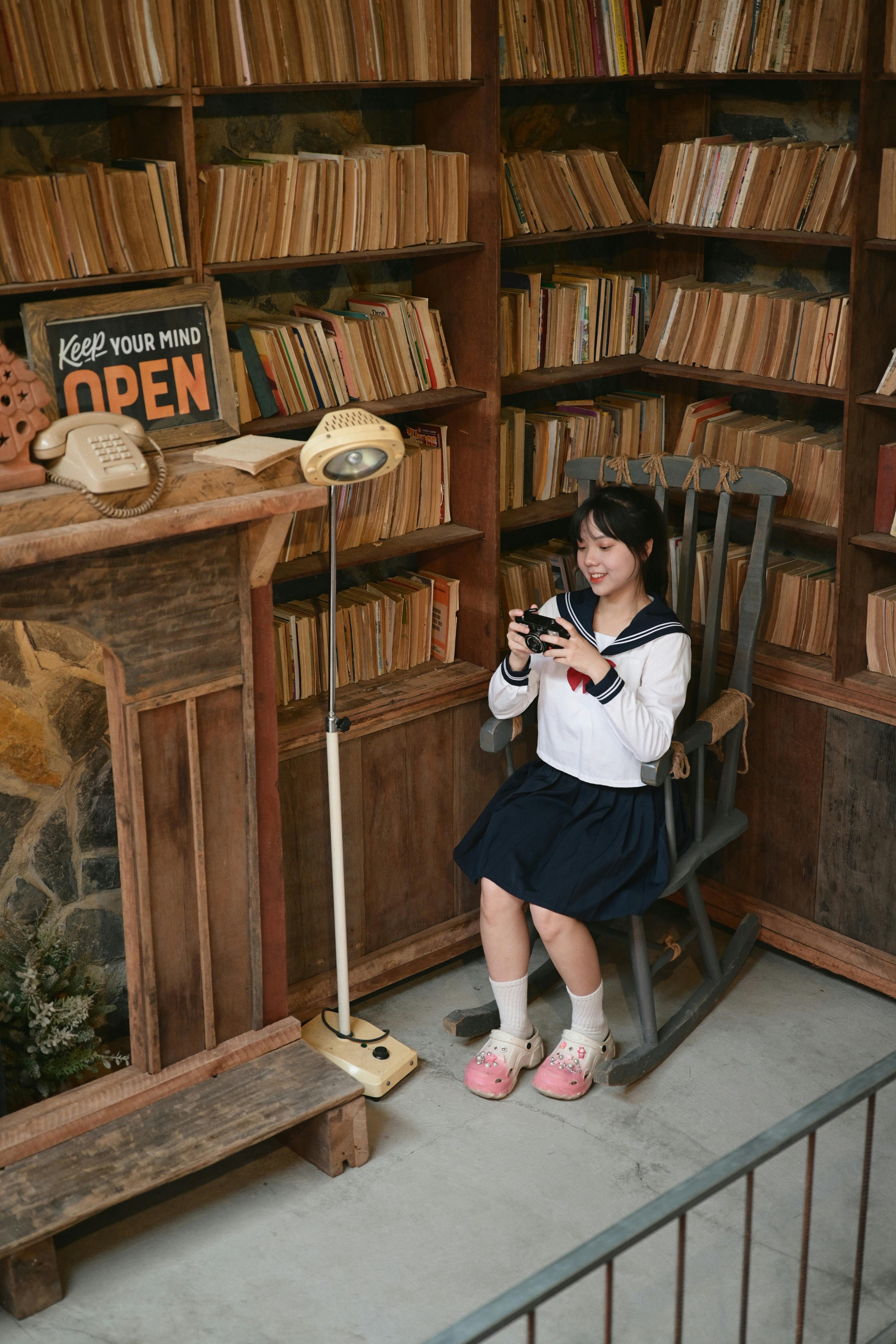 A young woman in a sailor suit reading in a cozy vintage library setting.
