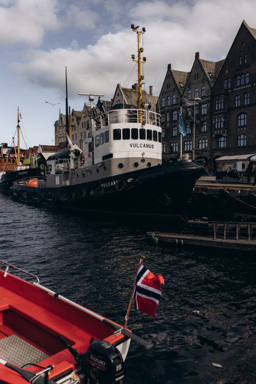 Free Tugboat Vulcanus at Bergen Harbor, Norway against historic architecture. Stock Photo