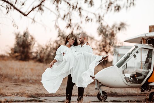 Bride and groom enjoying a sunset wedding shoot by an airplane, capturing true love and romance.