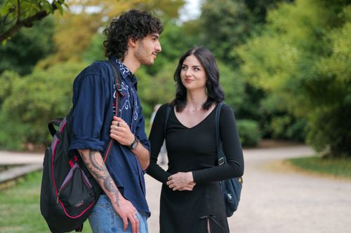 Free A young couple enjoying a conversation while walking in a lush, green park. Stock Photo