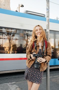A joyful adult woman holding a camera, standing by a tram in Istanbul.