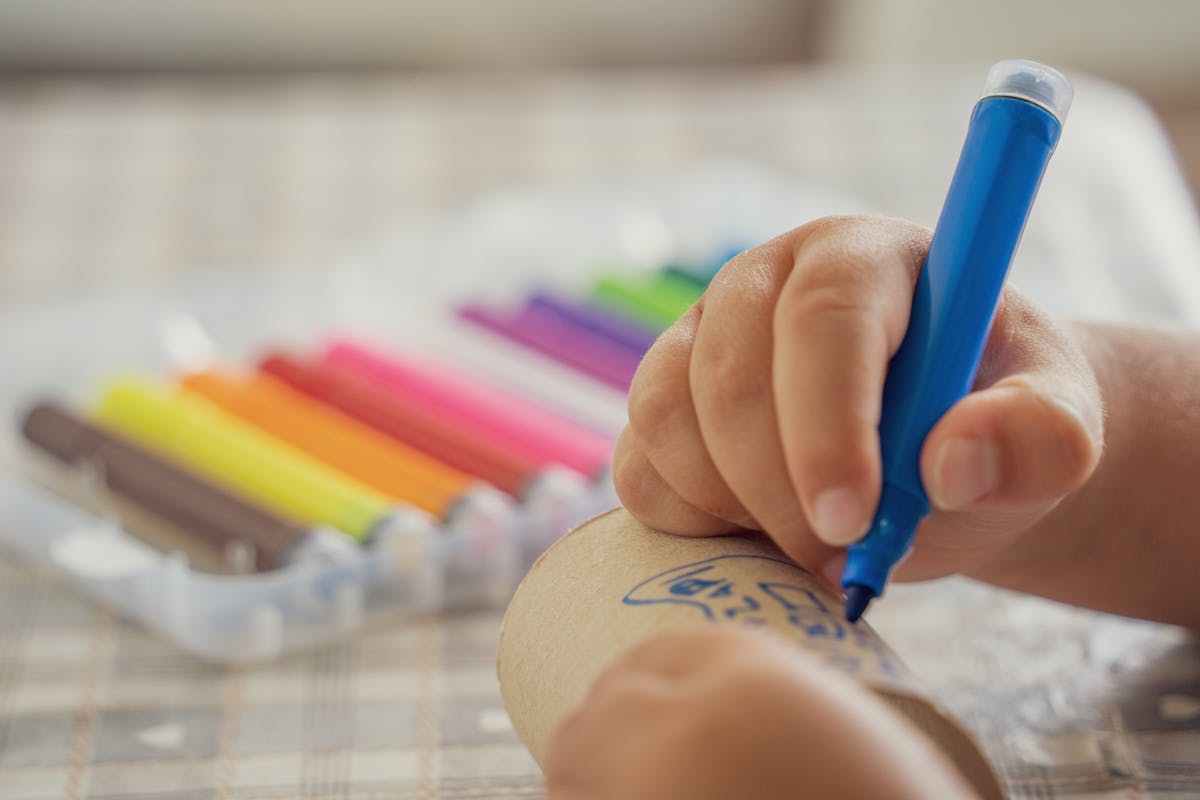 Bambino che disegna su carta spessa con pennarelli colorati