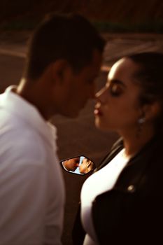 A couple shares a tender moment, reflected in a motorcycle mirror, evoking romance and connection.