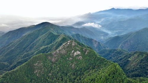 Free A breathtaking aerial view of a lush green mountain range shrouded in mist. Stock Photo