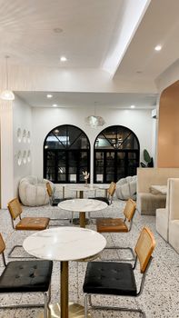 Elegant modern cafe interior with marble tables, arch windows, and stylish seating for a cozy ambiance.