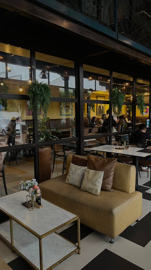 Free Warm interior of a modern cafe with cozy seating and lush greenery. Stock Photo