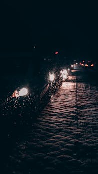 雨夜中，汽车停在路上，前灯在潮湿的路面反射着光