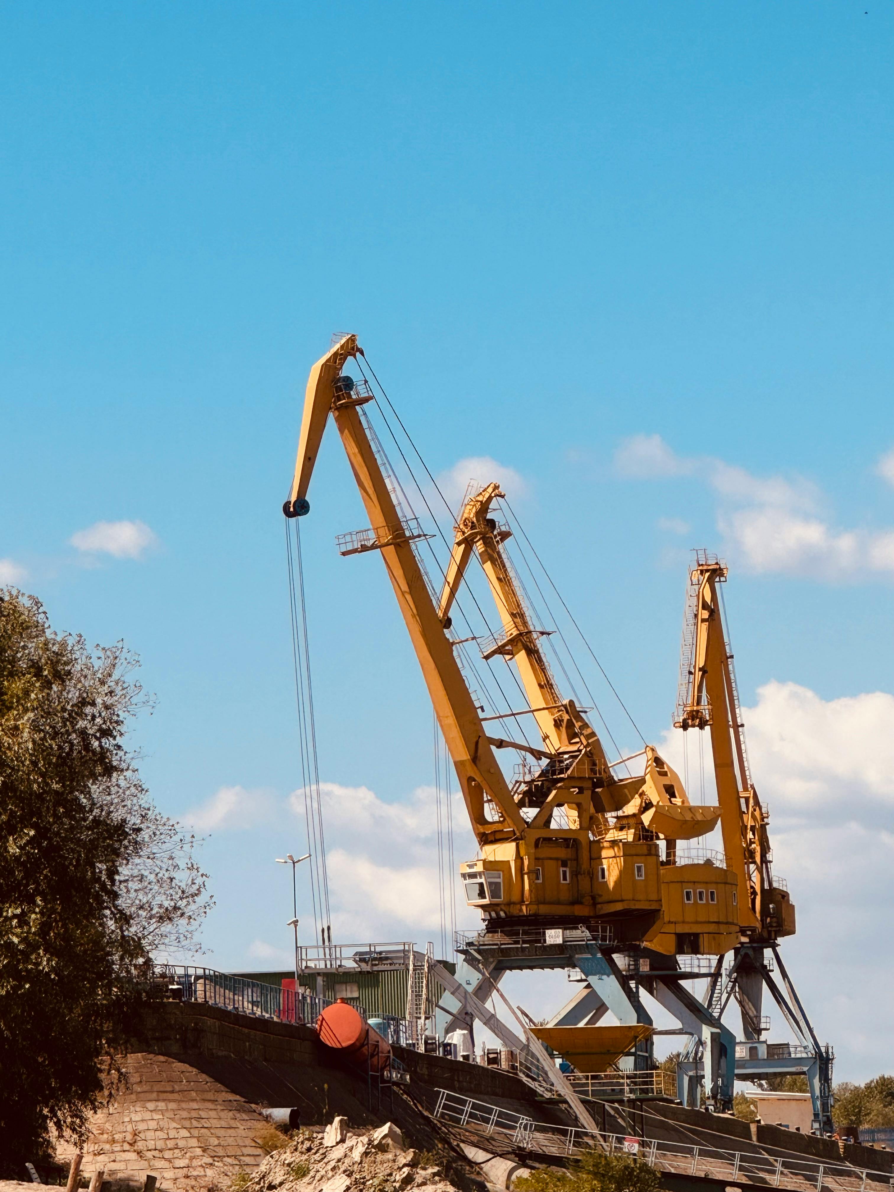 Majestic industrial cranes dominate the skyline against a clear, blue backdrop.
