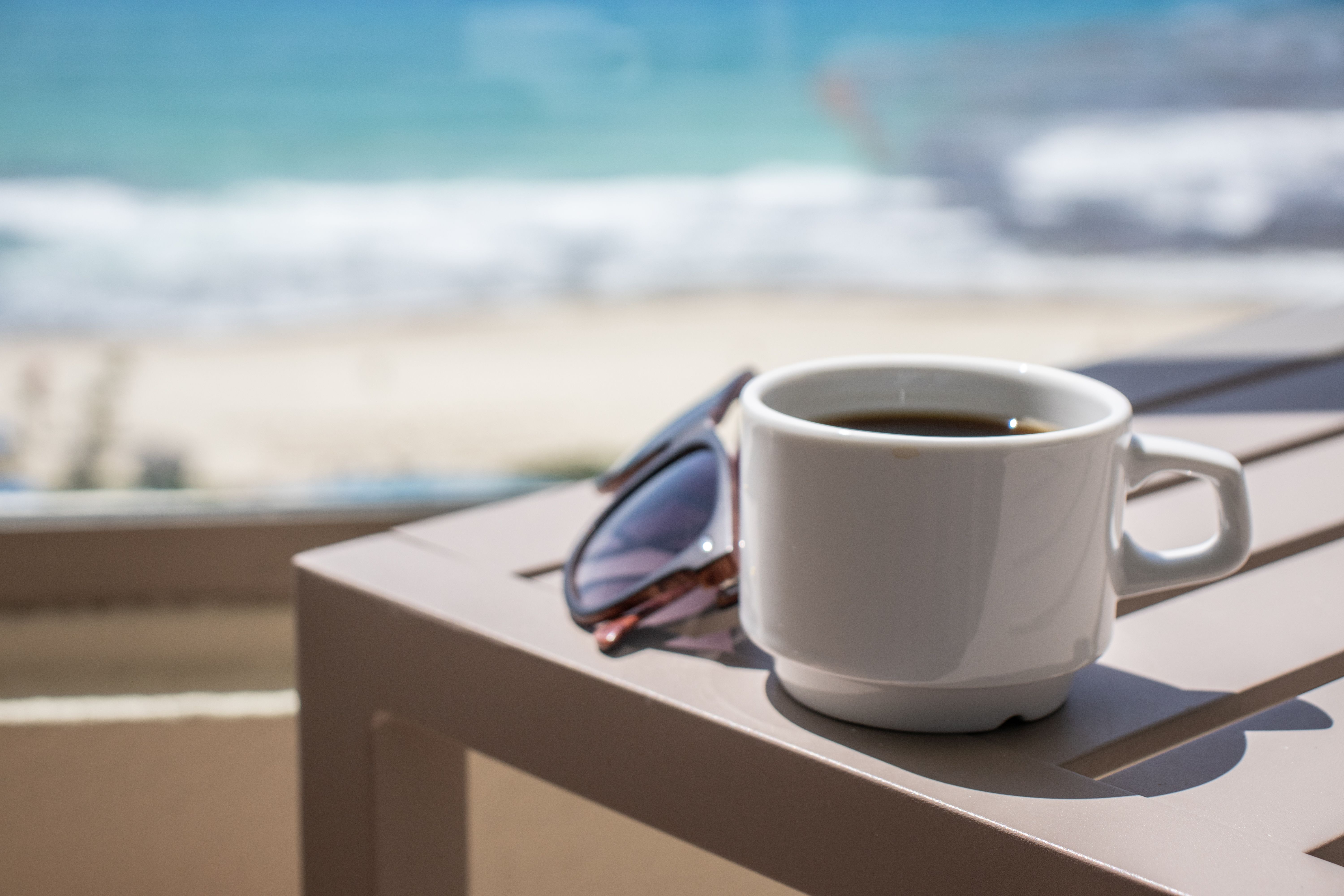 Coffee Cup and Sunglasses by the Beach  Free Stock Photo