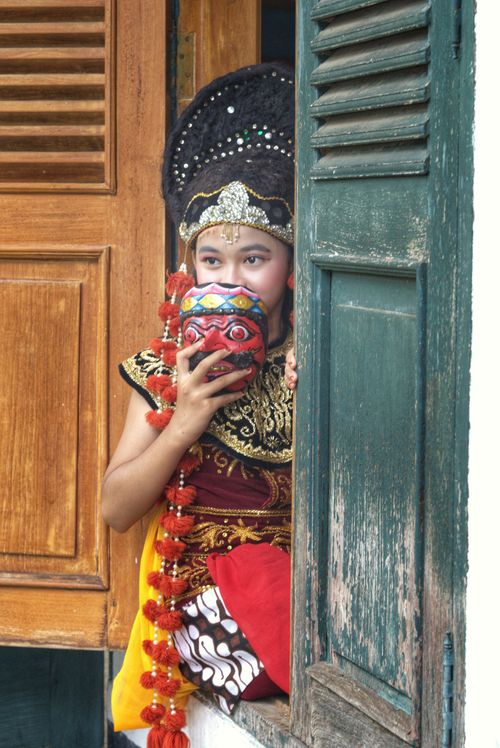 Free A young Indonesian dancer in vibrant traditional attire holds a mask, embodying cultural artistry. Stock Photo