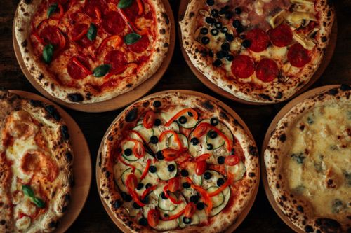 Free A selection of artisan pizzas with diverse toppings on wooden platters, showcasing rich textures and flavors. Stock Photo