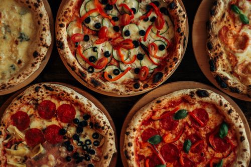 Free Top view of various gourmet pizzas with diverse toppings on wooden boards. Stock Photo
