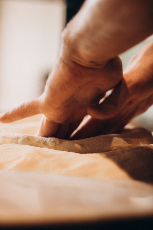 Free Close-up of hands kneading soft dough on a wooden surface, capturing the art of baking. Stock Photo