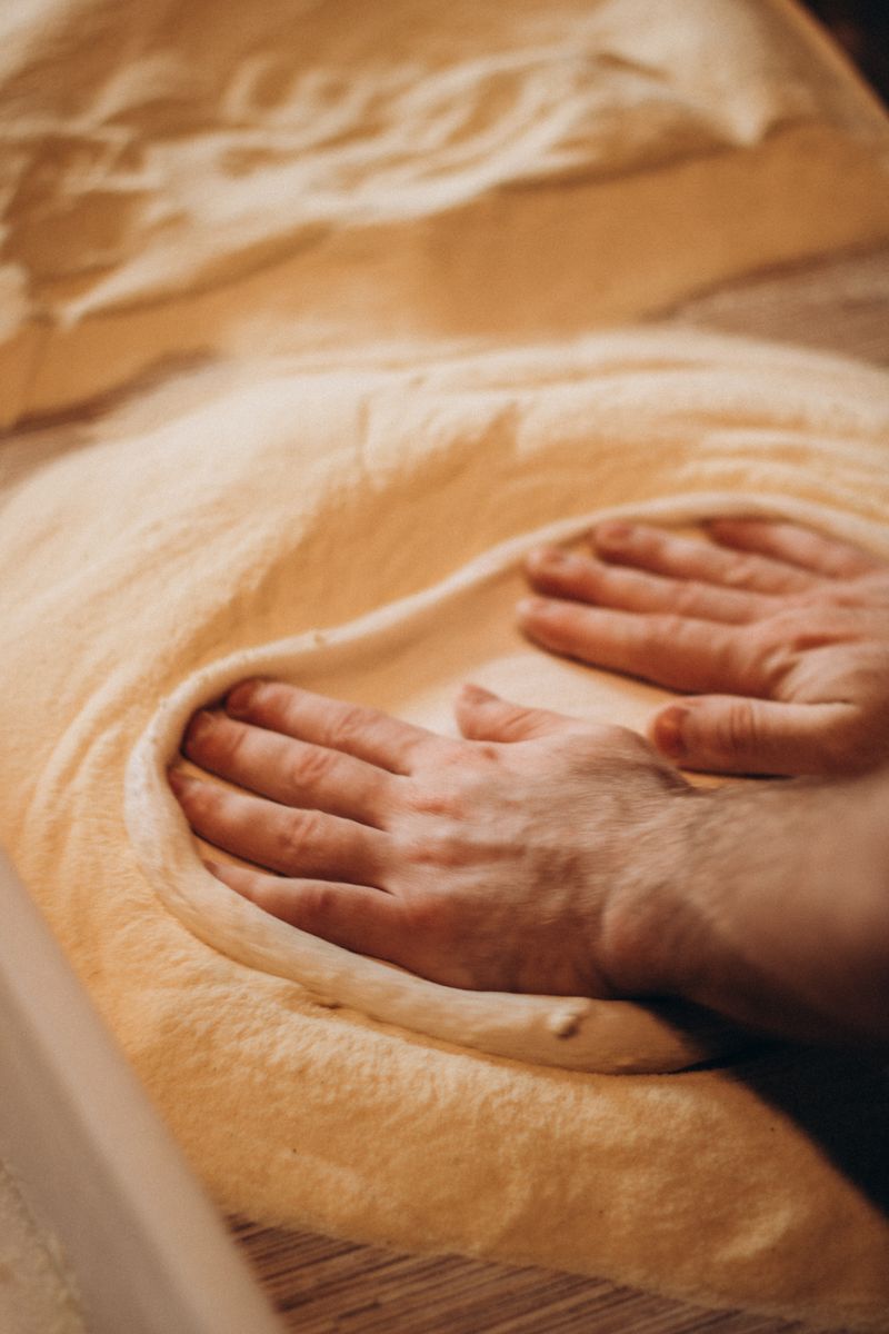 Close-up of hands kneading dough on wooden surface, highlighting traditional bread making.