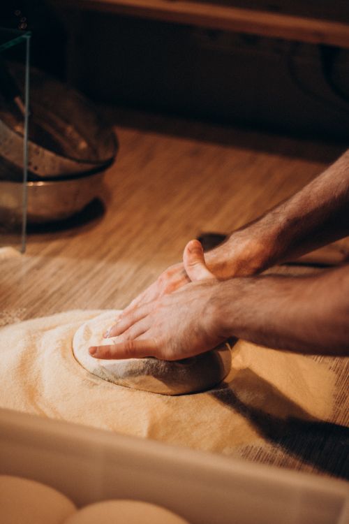 Free Close-up of hands kneading dough in a warm, rustic setting, emphasizing traditional baking techniques. Stock Photo