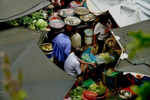 A bustling outdoor street market with fresh produce and seafood, viewed from above.
