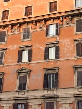 Orange facade of an Italian building with classic shutters, in Rome, Lazio, Italy.