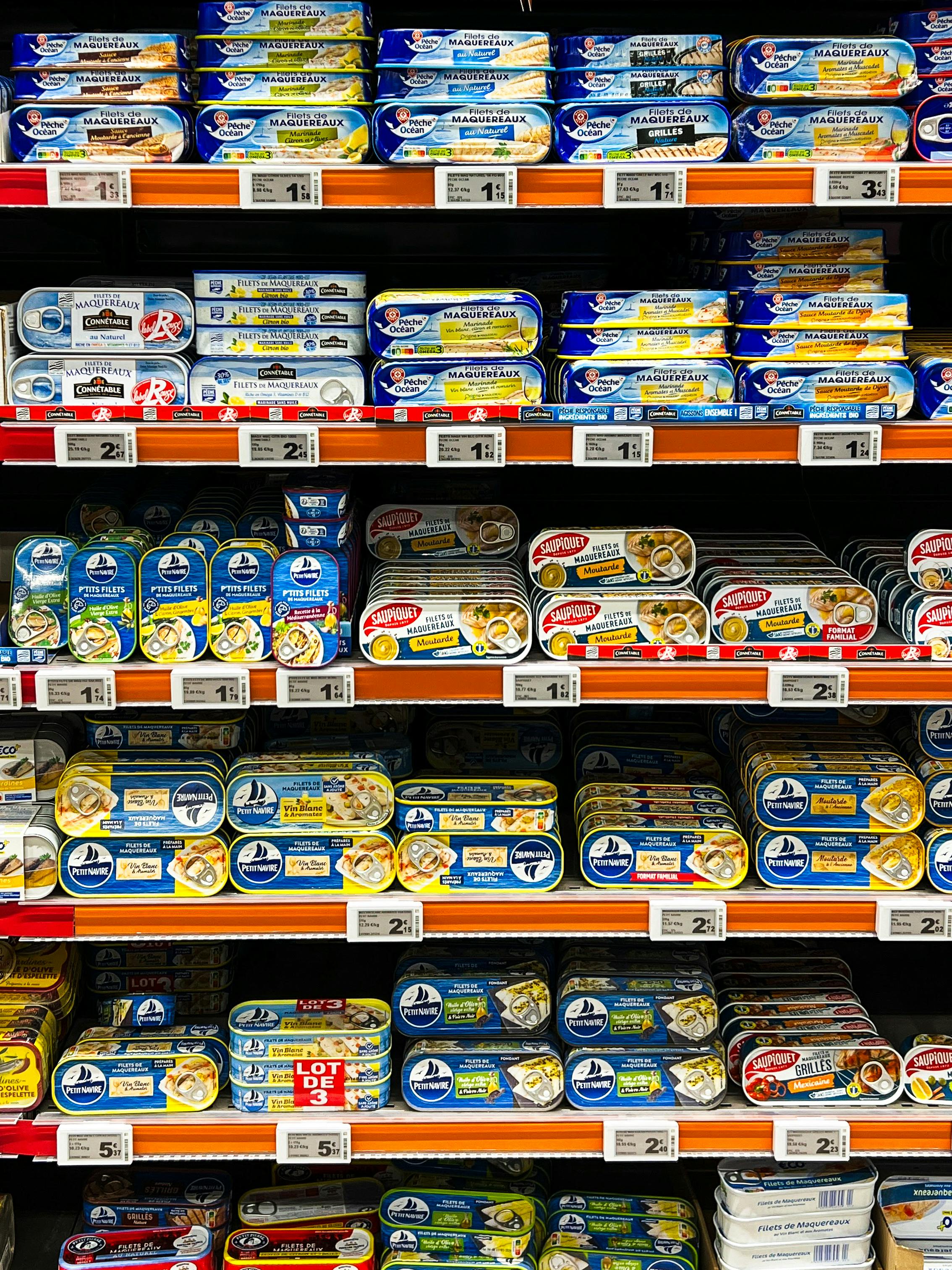Vibrant selection of canned fish in a French supermarket aisle.