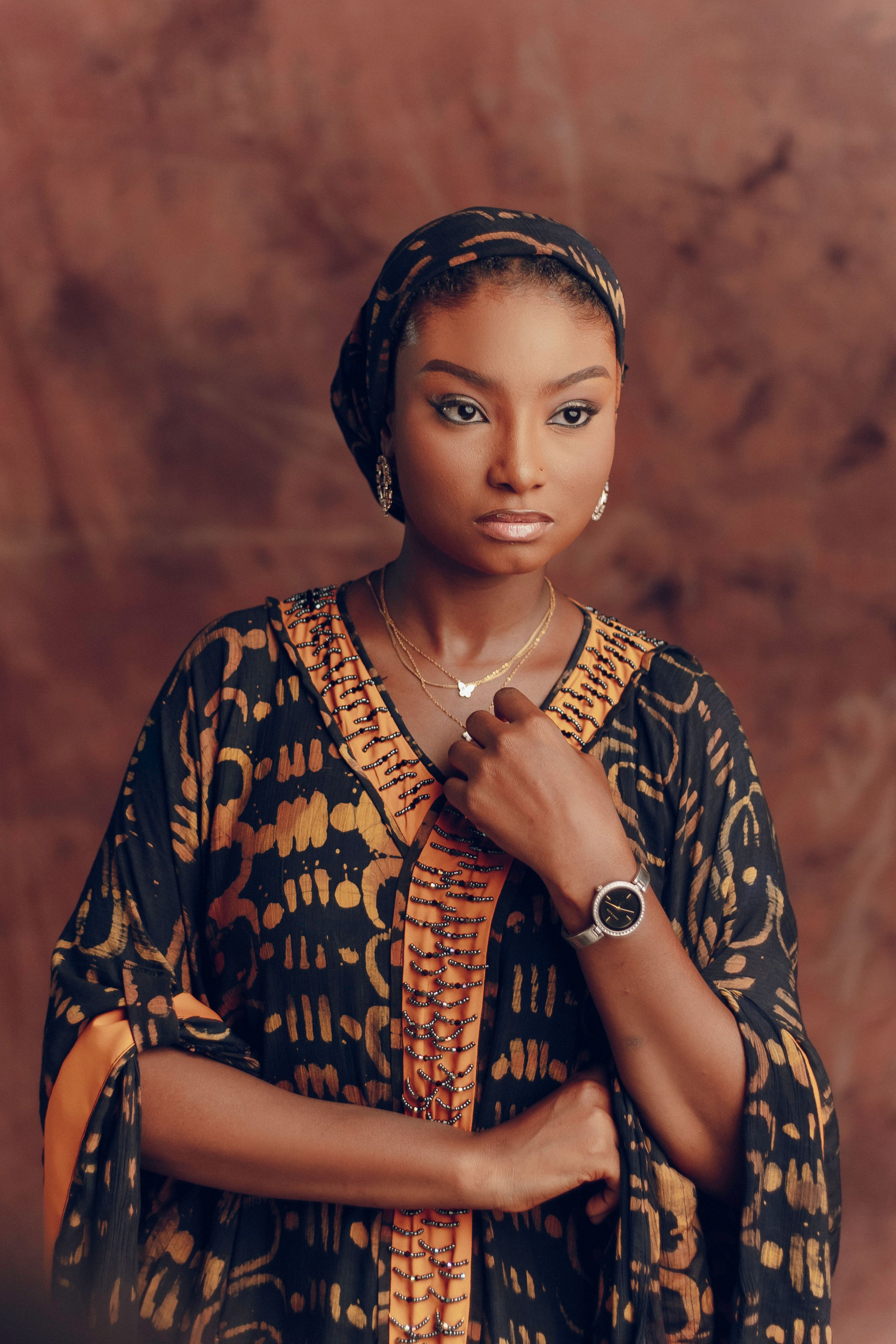 Graceful woman in traditional attire with elegant jewelry, set against a warm backdrop.