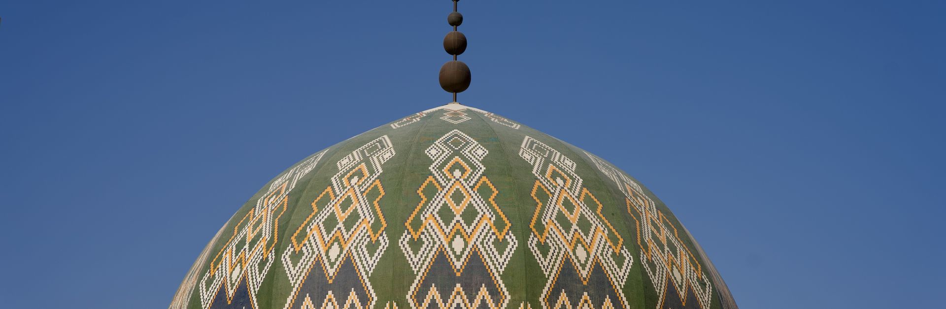 Captivating geometric patterns on a mosque dome in Riyadh, Saudi Arabia against a clear blue sky.