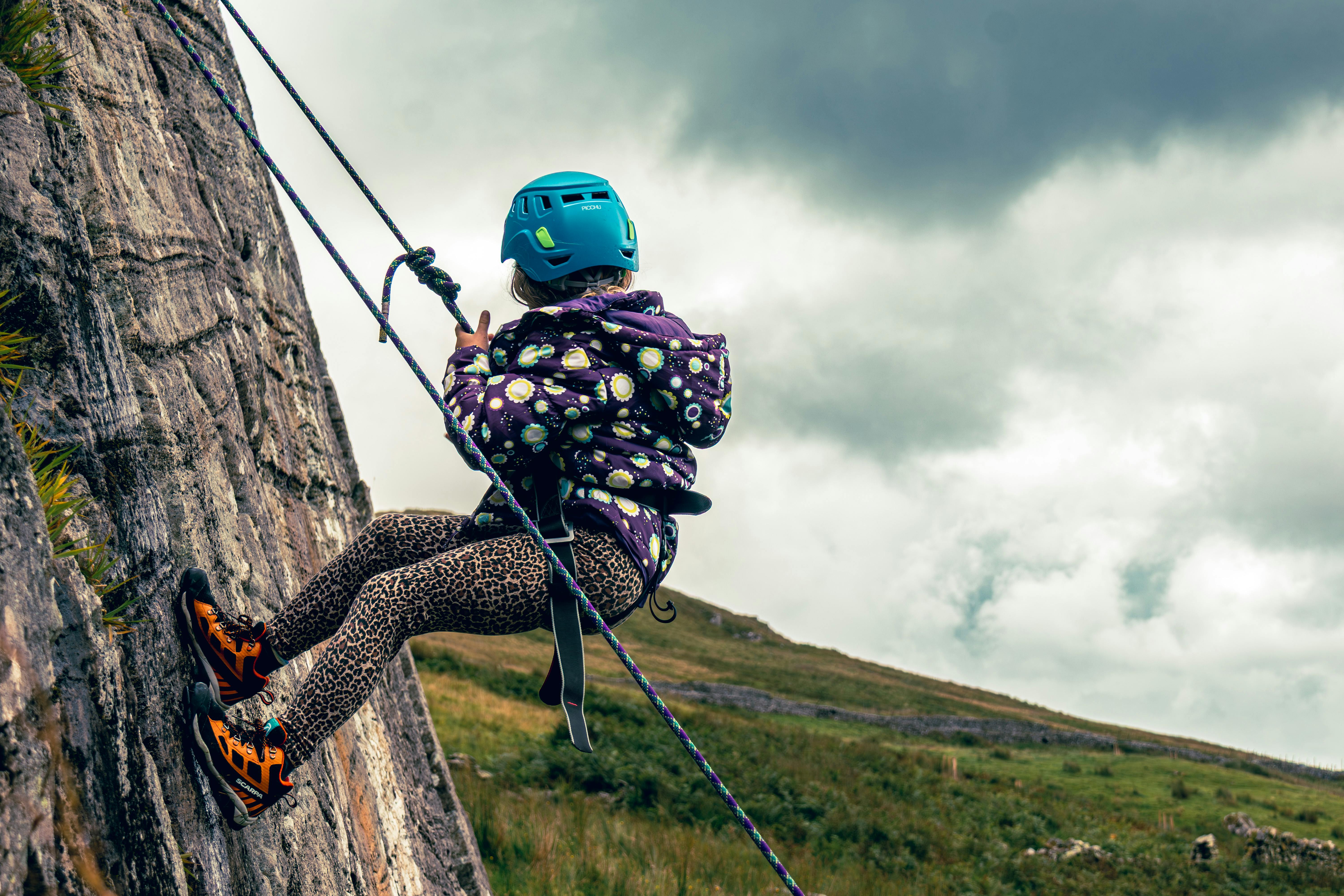 Young girl rock climbing on a cloudy day in the English countryside, showcasing adventurous spirit a