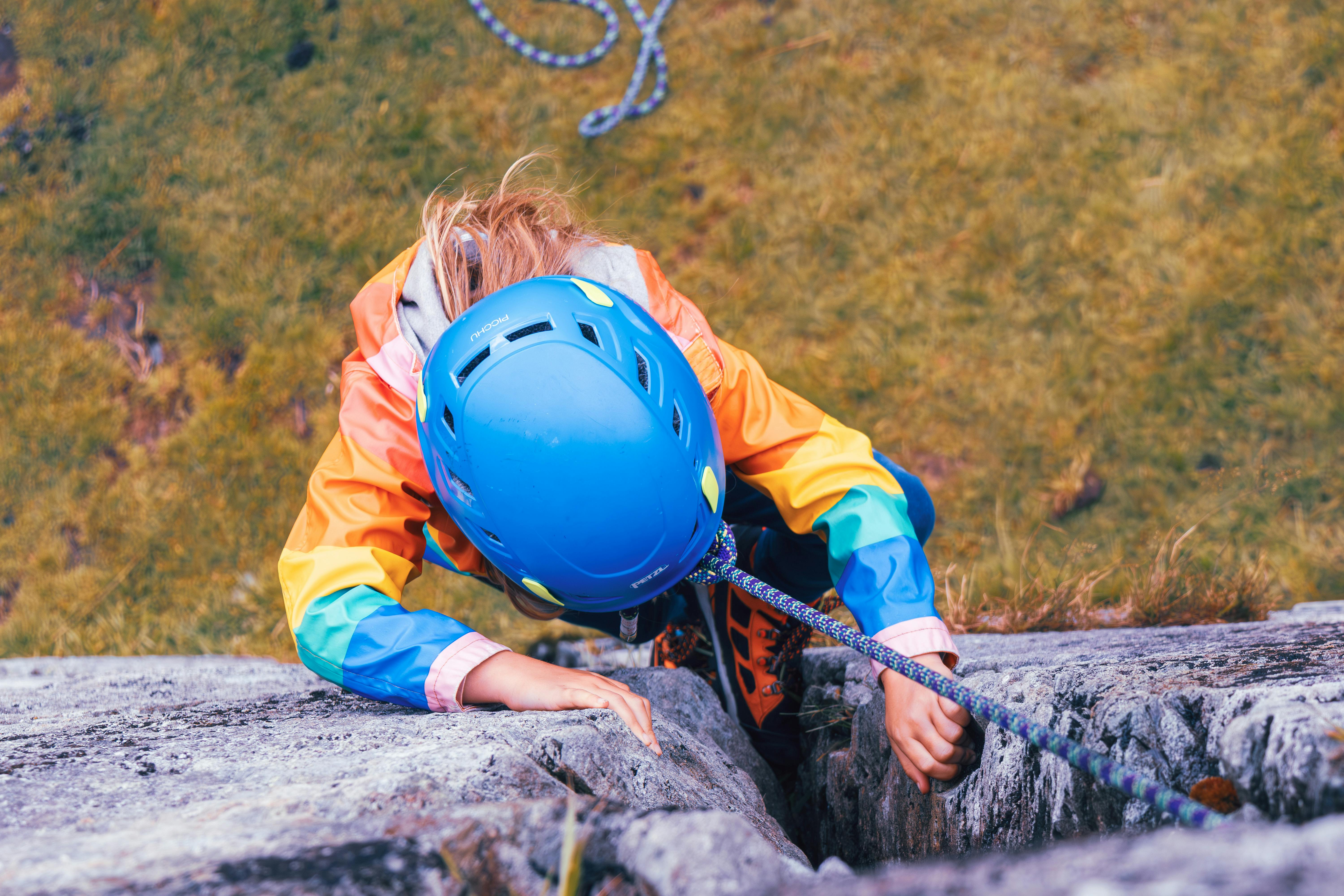 Young child rock climbs with safety gear in England, showcasing a vibrant and adventurous spirit.