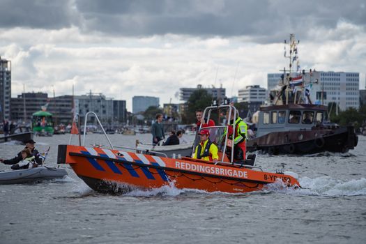 Rescue boat from Reddingsbrigade navigating busy urban waters, showcasing teamwork.