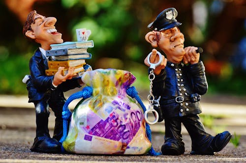 Policeman Holding Handcuffs and Man Wearing Blue Suit Carrying Books Figures on Brown Surface