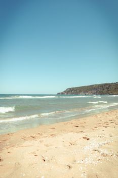A tranquil beach scene featuring gentle waves and a clear sky, perfect for a summer day.