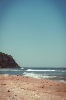 A serene beach view with gentle waves under a clear blue sky.
