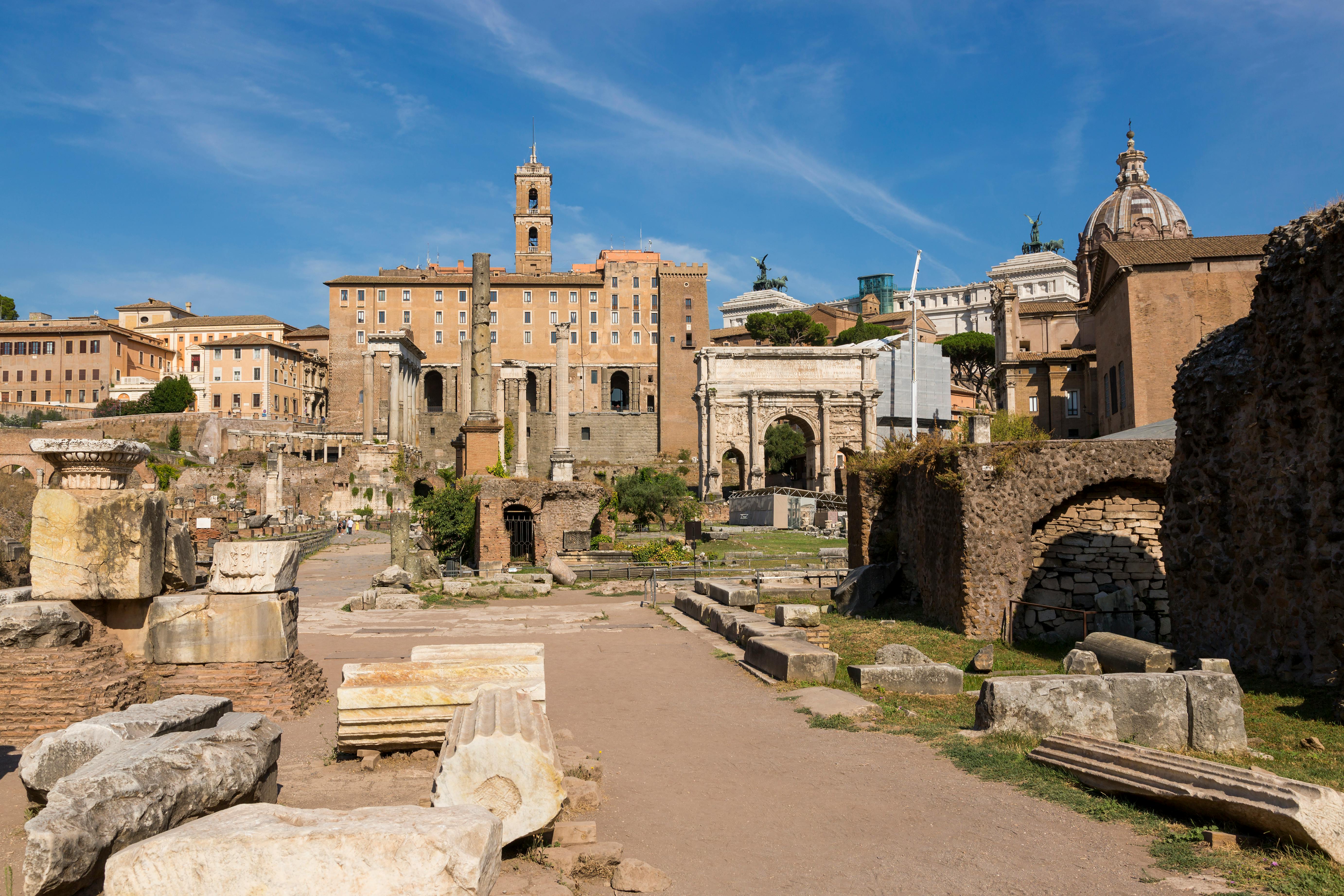 Explore the historic ruins of the Roman Forum in Rome under a bright blue sky.