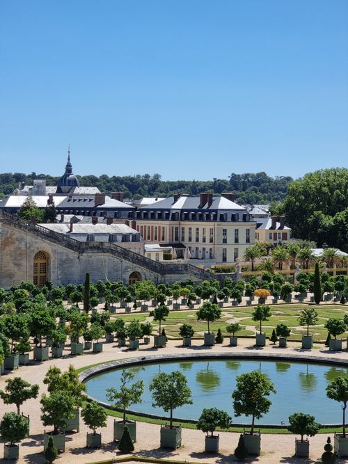 Free A scenic view of the Versailles garden with historical architecture under a clear blue sky. Stock Photo