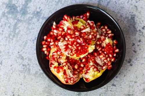 Free Vibrant pomegranate seeds fill a black bowl, highlighting their natural beauty. Stock Photo