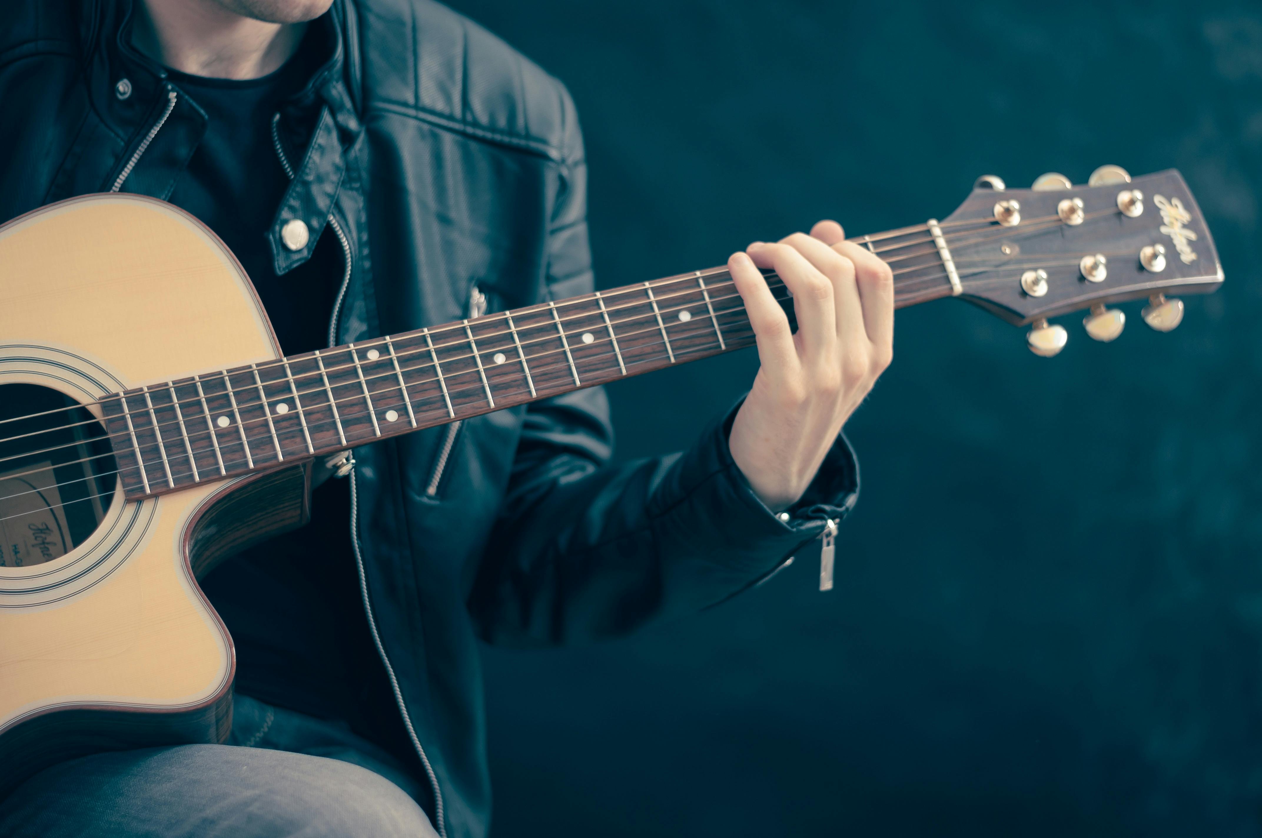 A person holding a brown and black guitar