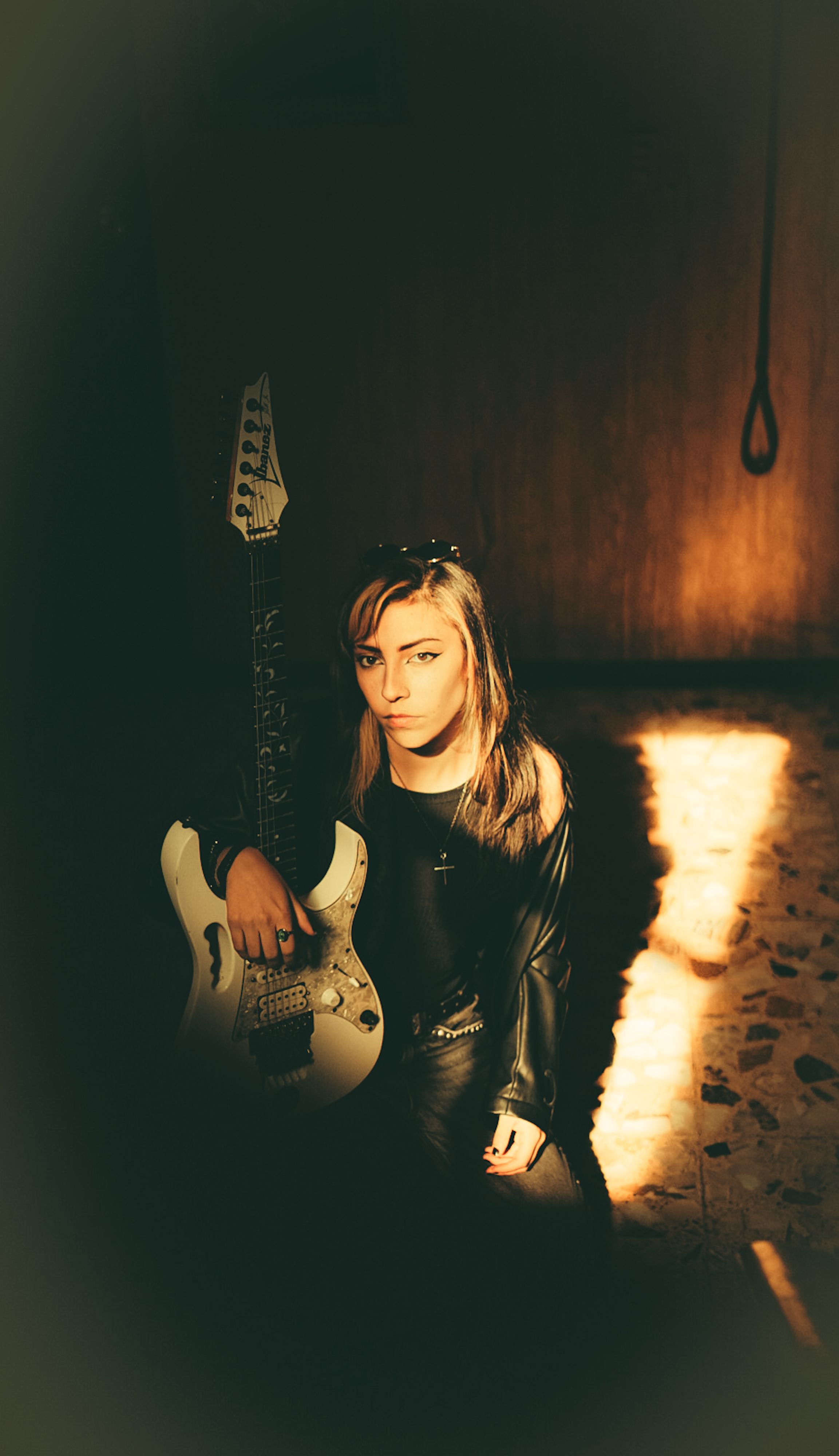 Artistic portrait of a woman with an electric guitar in warm lighting.