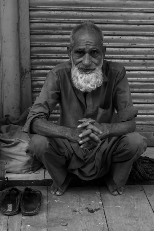 Free Black and white portrait of a senior man sitting on a street in New Delhi, India. Stock Photo