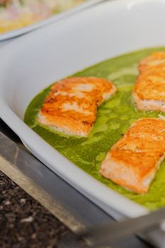 Delicious grilled salmon fillets in a vibrant basil sauce, served in a white dish.