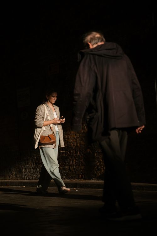 Free A candid street photo capturing two people passing by in London at night. Stock Photo
