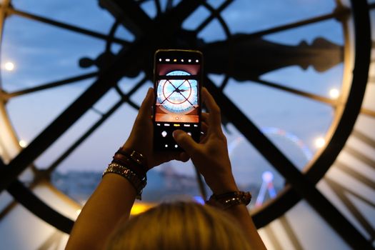 View of a clock through a phone at sunset, inside a museum. Perfect travel moment.
