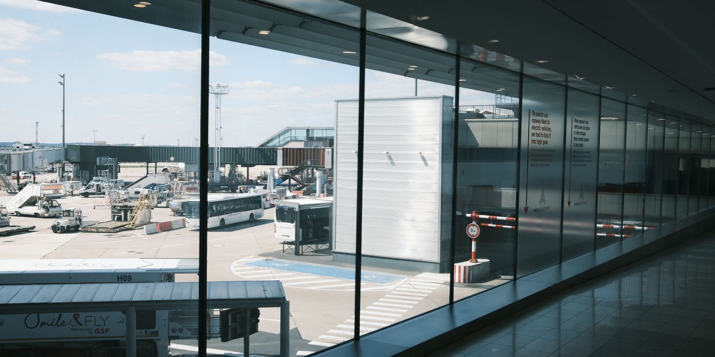 Wide view of an airport terminal concourse with travellers walking toward the gates