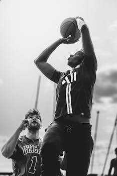 Black and white action shot of two basketball players in mid-game, highlighting athleticism and competition.