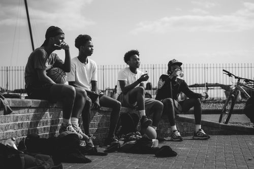 Free Black and white photo of teenagers sitting by the seaside, enjoying a relaxed moment. Stock Photo