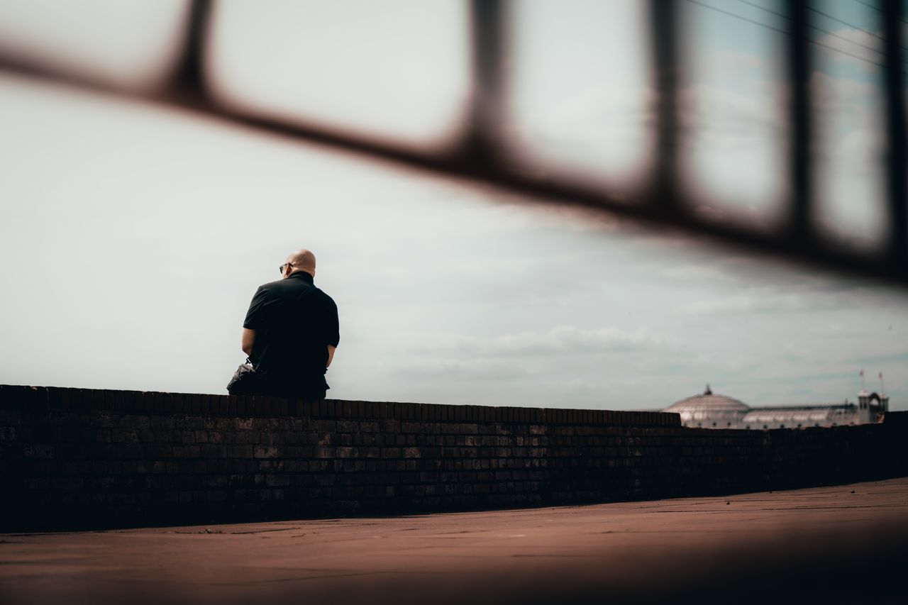 a solitary man sits contemplatively on a wall in brighton and hove eng