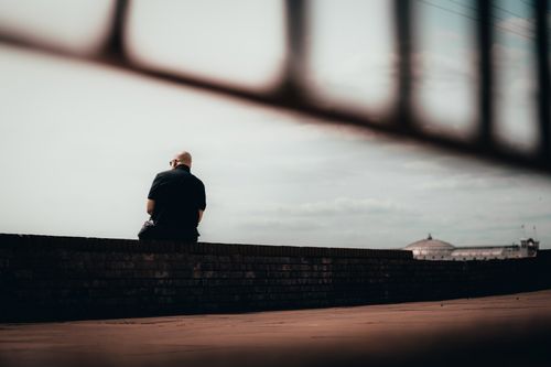 Free A solitary man sits contemplatively on a wall in Brighton and Hove, England. Stock Photo