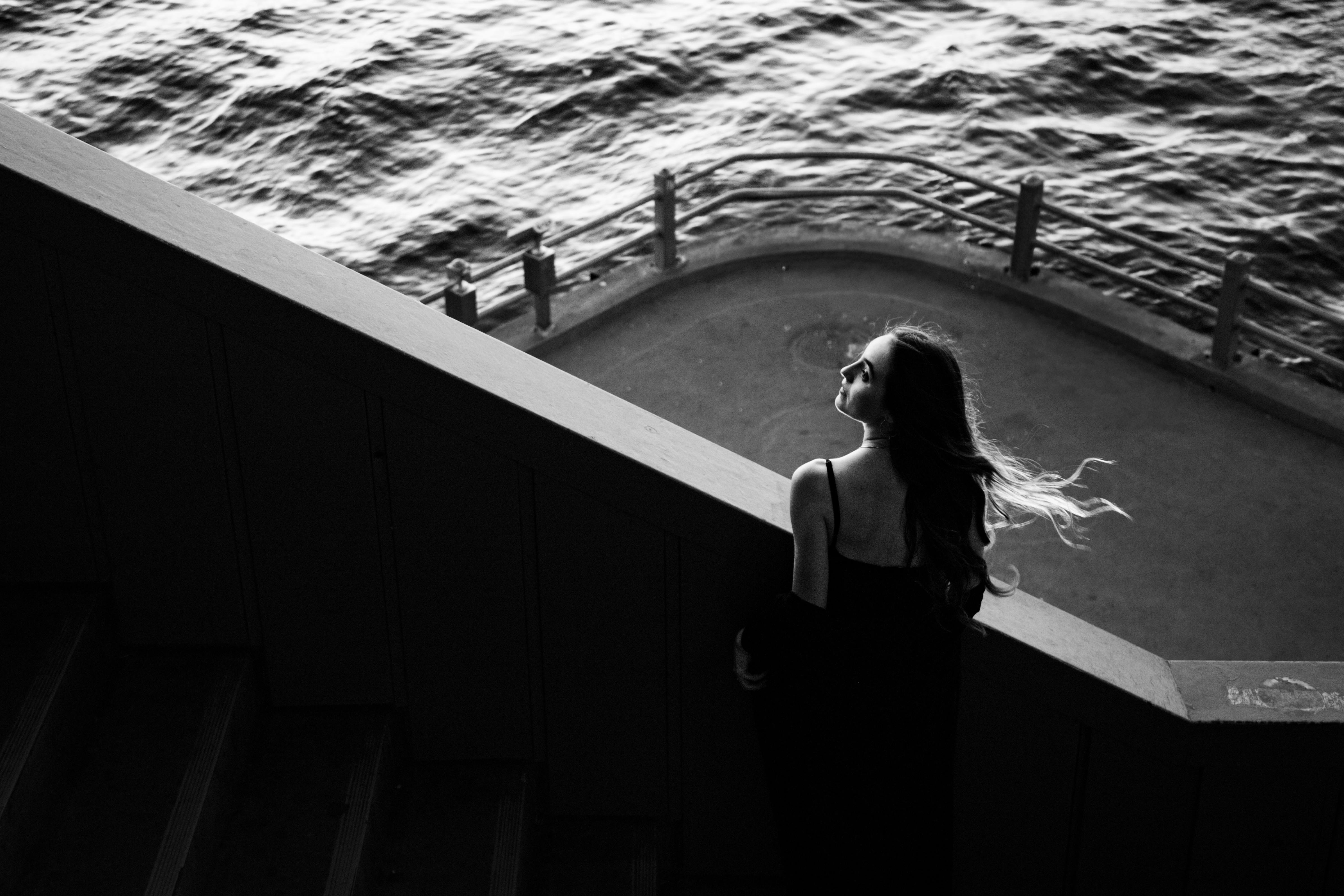 Dramatic black and white portrait of a woman by the waterfront in Istanbul, exuding elegance and mystery.