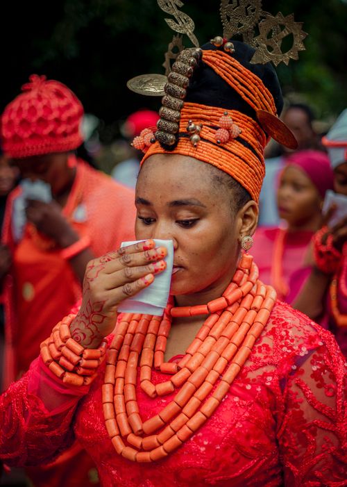 Free Woman in vibrant traditional Nigerian attire sipping a drink during a cultural festival. Stock Photo