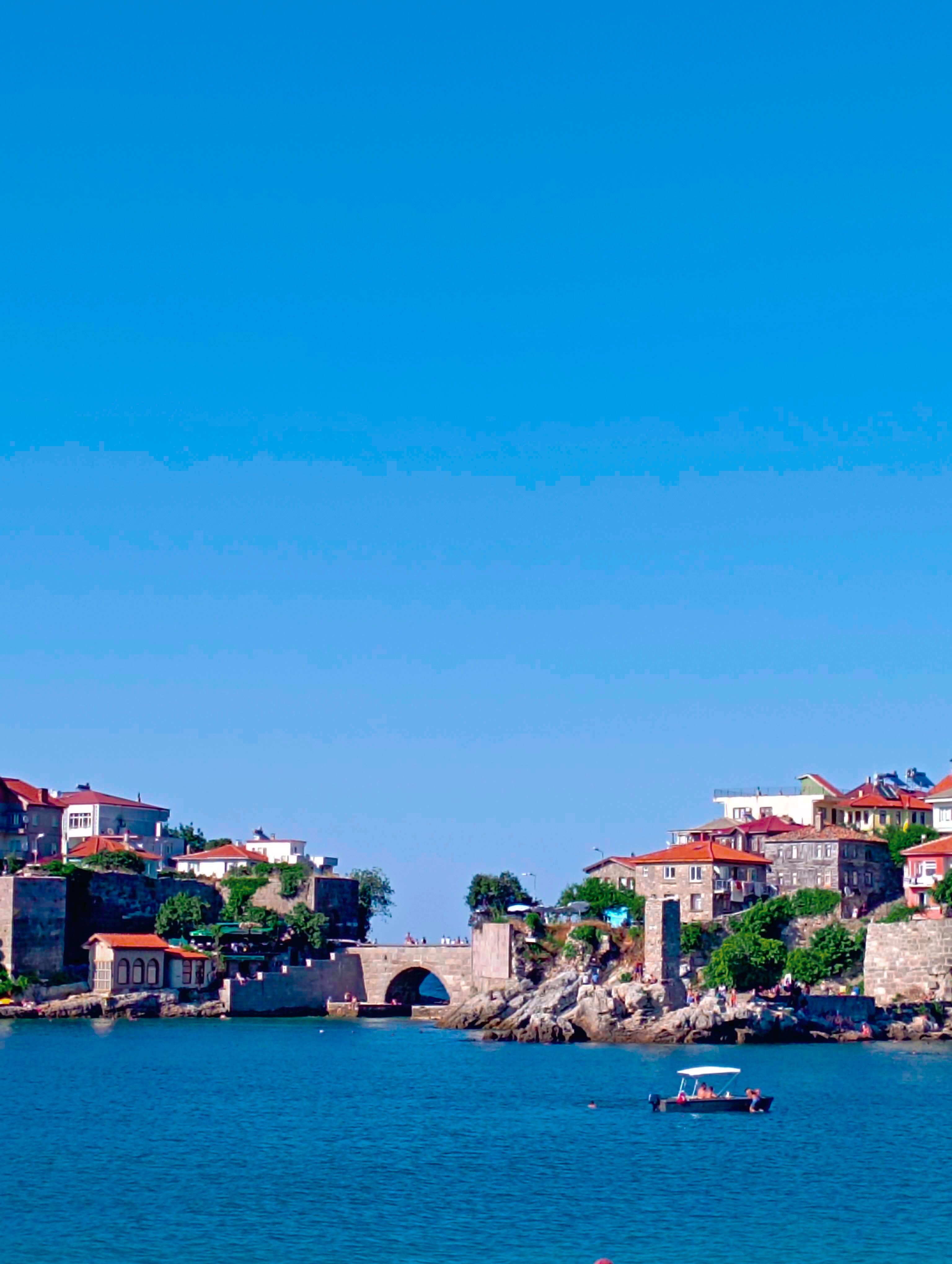 Explore the picturesque stone village by the sea under a bright blue sky, perfect for travel and architecture lovers.