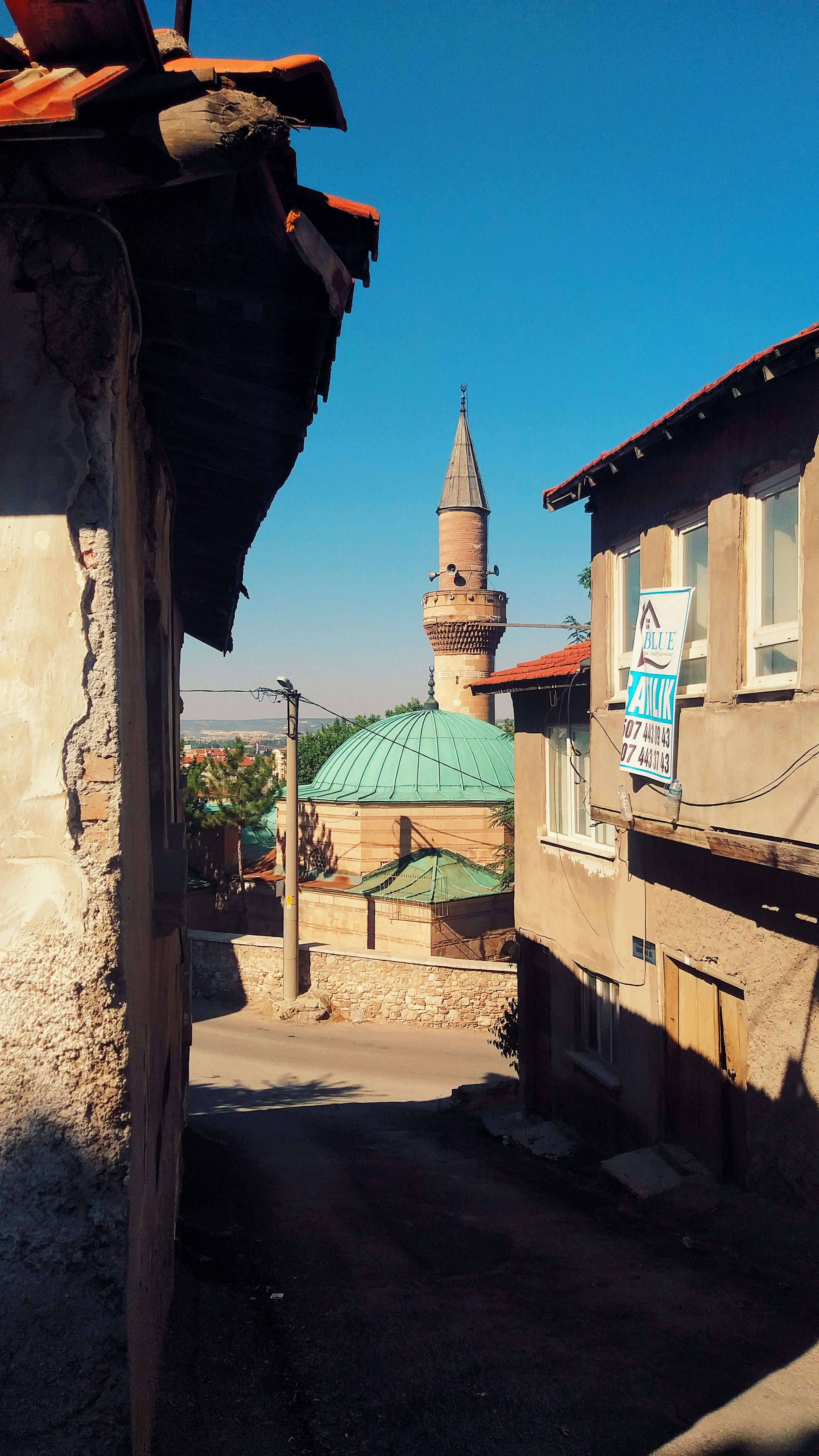 A picturesque street in Kütahya, Türkiye, showcasing a mosque under a clear blue sky.