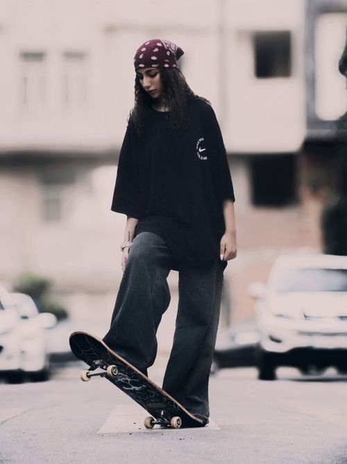 Free Stylish young woman skateboarding on an urban street, showcasing street culture and fashion. Stock Photo