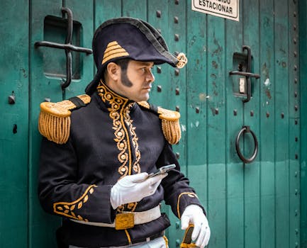 Man in historical military costume with mobile phone in front of green door.